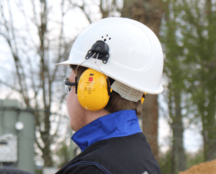 eine Person trägt einen weißen Schutzhelm und gelben Gehörschutz