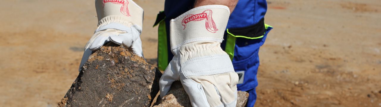 Arbeitshandschuhe aus Leder mit Steinen in der Hand